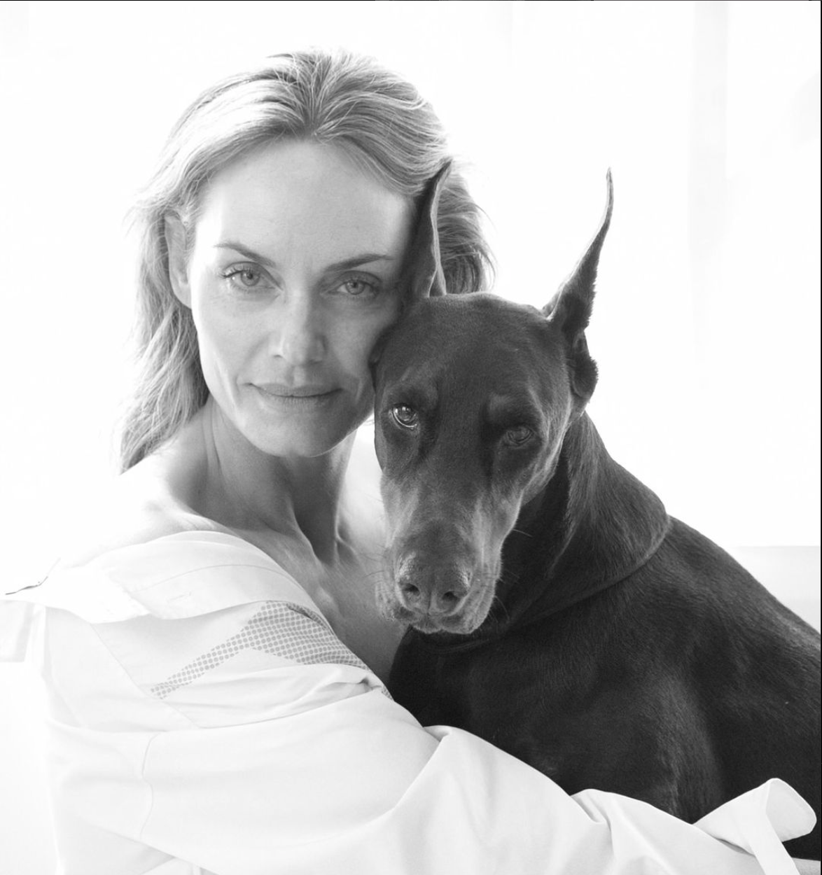 Amber Valletta, supermodel, fashion icon, actress, and social entrepreneur, posing with her Doberman dog, Bella. They are closely posed, both looking directly at the camera.