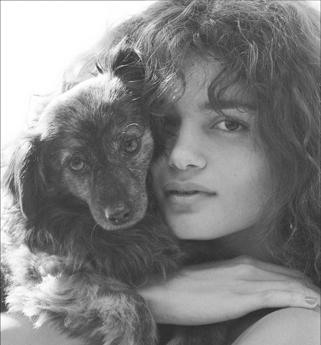 Vie Chidac, a model, holding her dog Chip close. Both are captured in a close-up, highlighting their bond.